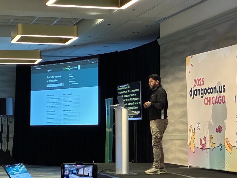 Rizwan standing on a stage behind a podium with a screen showing a slide about the government of Ireland migrating to Wagtail behind him.