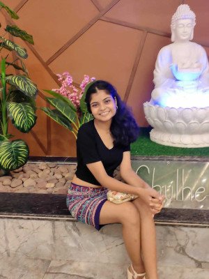 This is a picture of Anuja Raj Verma smiling for the camera with a white glowing statue of Buddha behind her