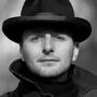 A headshot of Maurice Haak wearing a spiffy bowler hat.