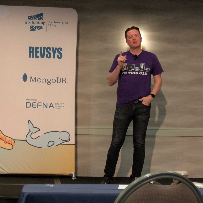 Tim Allen holding a finger up and smiling as he gives a talk about his past decade of adventures and misadventures in the Django community.