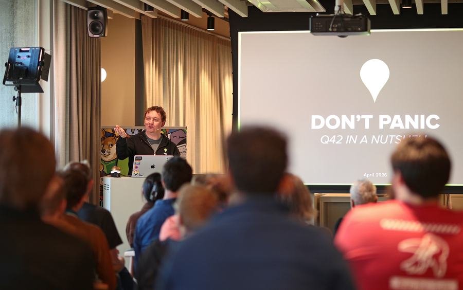 A speaker giving a talk behind a podium to a full audience at the Q42 office.