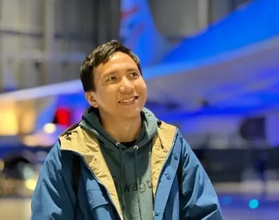 Sage Abdullah smiling in front of a space shuttle.