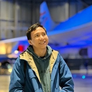 Sage Abdullah smiling in front of a space shuttle.