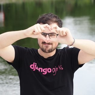 Thibaud Colas making a heart shape with his fingers in front of his face while wearing a Django Girls t-shirt.
