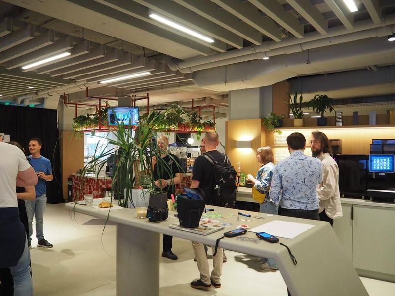 Attendees chatting in the open venue area beside plants, tables, and Wagtail Space signage