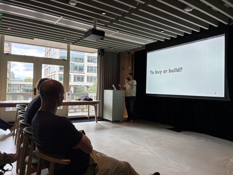 Presenter addressing the room beside a slide reading To buy or build during a Wagtail Space session
