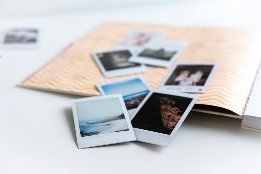 Polaroid photos spilling out of a photo album onto a table